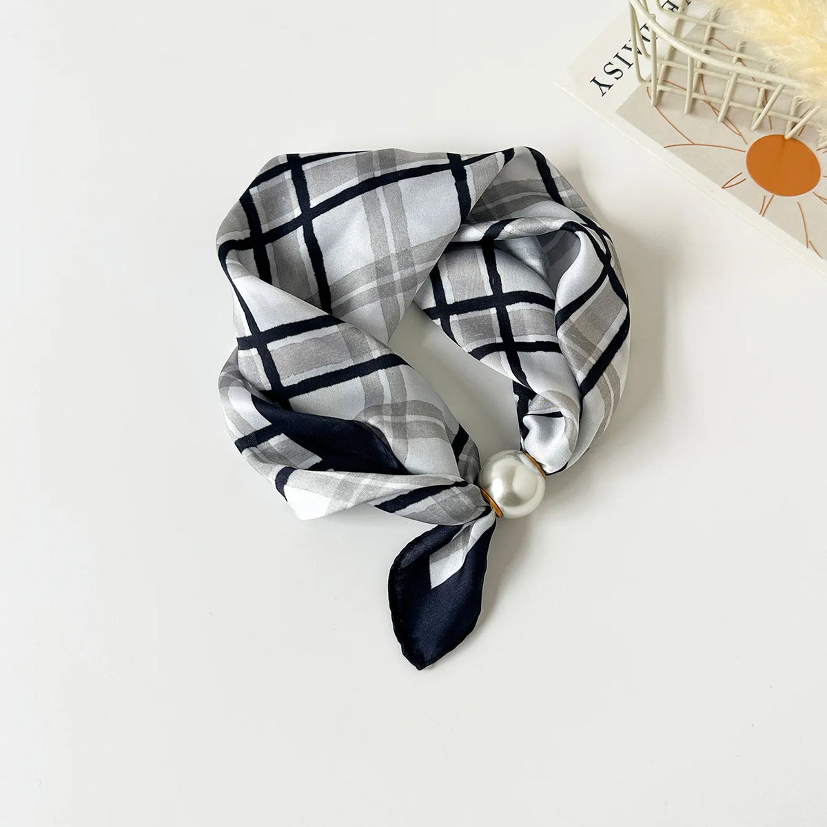 A black and gray plaid silk scarf tied in a knot with a pearl bead detail.