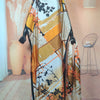 A long, flowing kaftan dress in beige and orange floral print displayed on a mannequin.