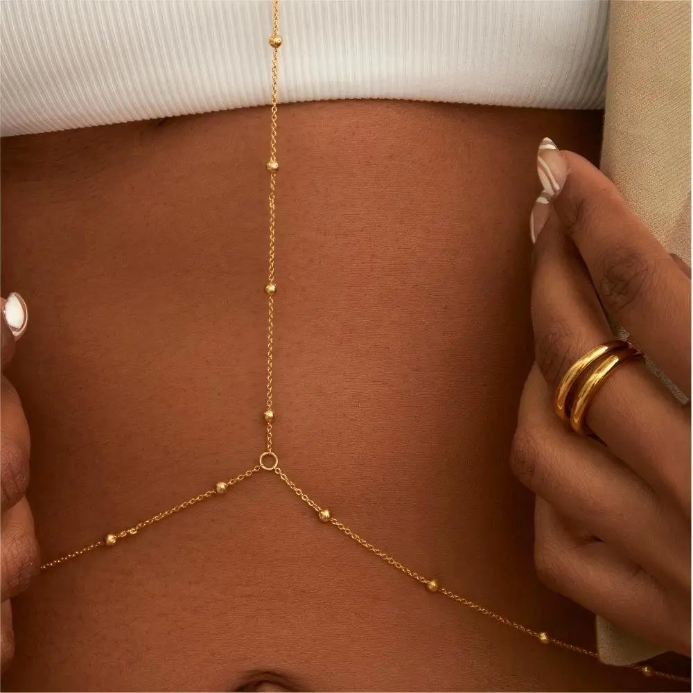 A close-up of a gold adjustable belly chain body jewelry worn on a person's torso.