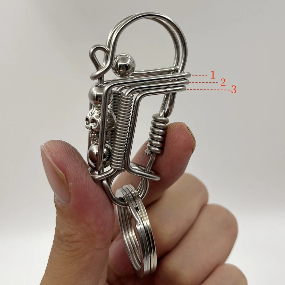 Un porte-clés mécanique en acier inoxydable avec un crochet et un ressort tenu dans une main.