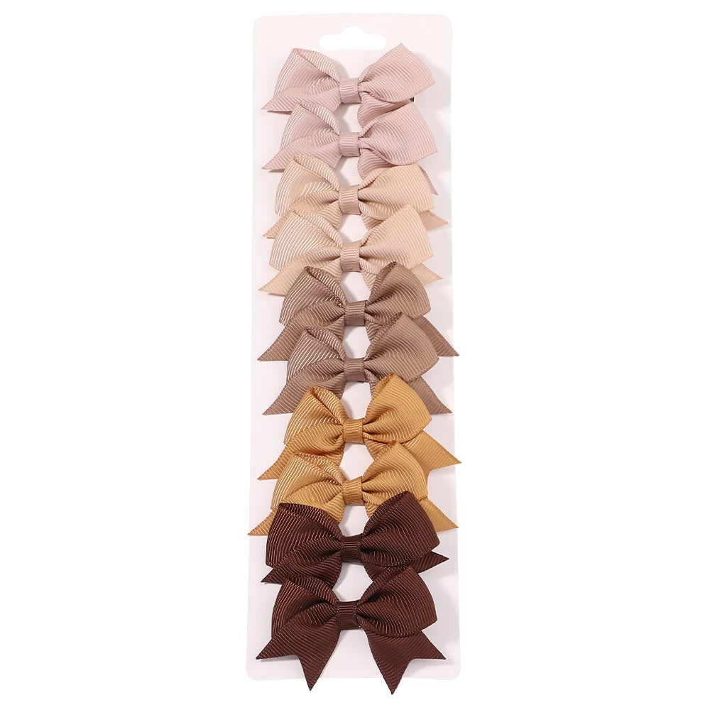 Un set de nueve clips para el pelo en forma de lazo de colores sólidos para niños en tonos beige, canela y marrón.