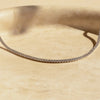 Primer plano de un collar choker con circonitas de hielo sobre una superficie beige claro.