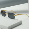 Gold-rimmed, dark gray square sunglasses resting on a white surface.