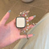 A hand holds a square digital watch with a clear face and a delicate double chain watch strap made of light pink beads.