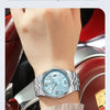 A close-up of a silver quartz watch with a blue dial and luminous features worn on a wrist.