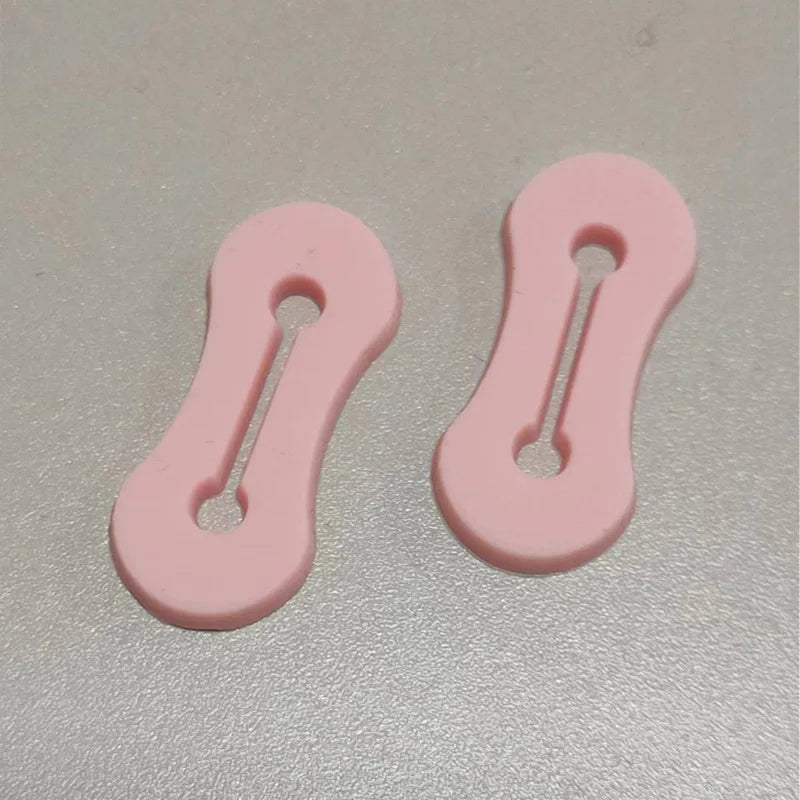 Un par de hebillas ajustables para extensiones de manga de camisa rosa.
