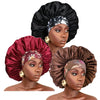 A model wears a black satin sleep bonnet with an elastic band and a floral patterned fabric.