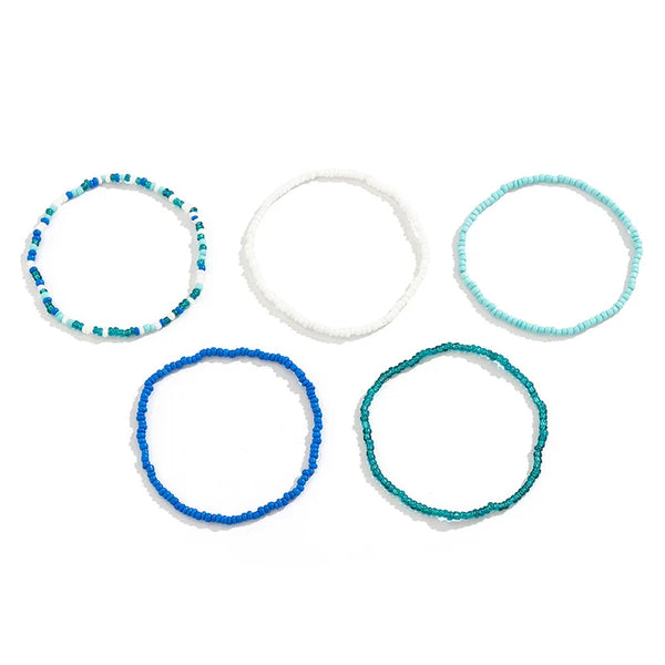 A set of four beaded anklets in various shades of blue and white.