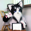 A black and white cartoon fox plush toy wearing furry gloves sitting on a wooden chair.
