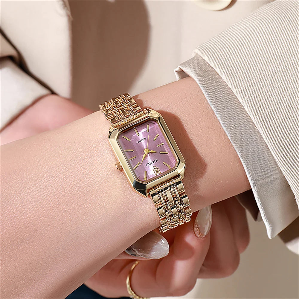 A close-up of an elegant gold plated quartz fashion watch with a purple stone and gold accents worn on a wrist.