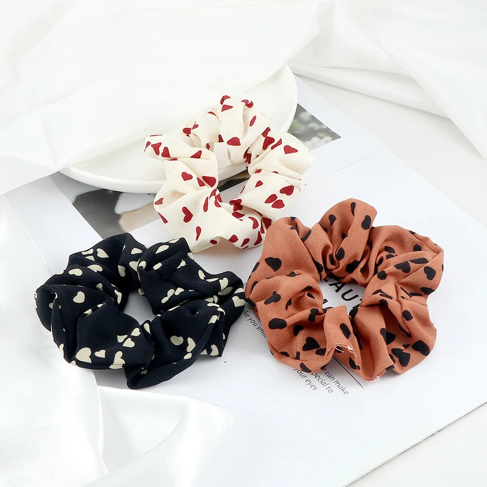 Three knitted fabric scrunchie headbands in floral and leopard print patterns displayed on white paper.