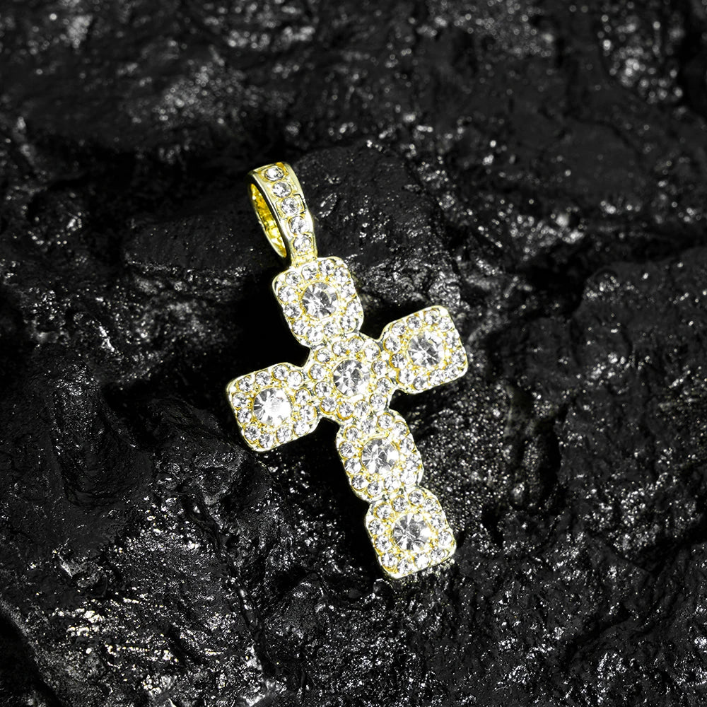 A sparkling rhinestone cross pendant necklace resting on a dark, textured surface.