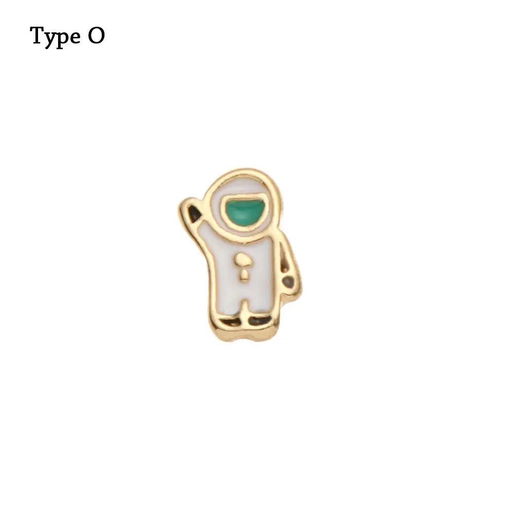 Adorno de pulsera de metal decorativo con forma de figura y detalle de gema verde.