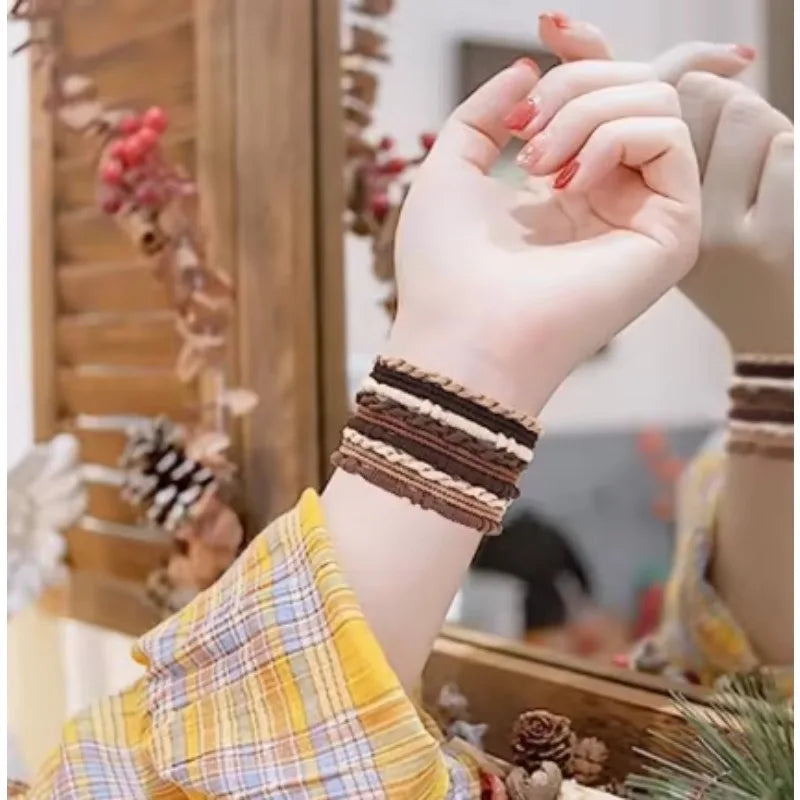 A hand wearing a stacked brown and beige beaded bracelet is visible next to some natural elements.