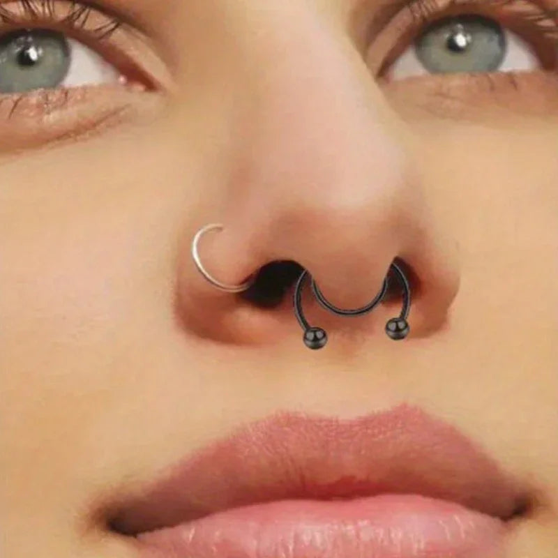 Close-up of a woman's nose with a silver hoop and small black nose ring set.