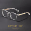 Clear acetate eyeglasses with gold accents resting on a dark surface.