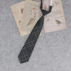 A plaid neck tie is displayed alongside vintage-style paper documents and a bird illustration.