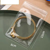 A clear self-sealing jewelry storage pouch containing a gold-colored ring, shown on a green plate.