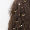 A close-up of dark brown hair adorned with ten small gold metal butterfly hair clips.