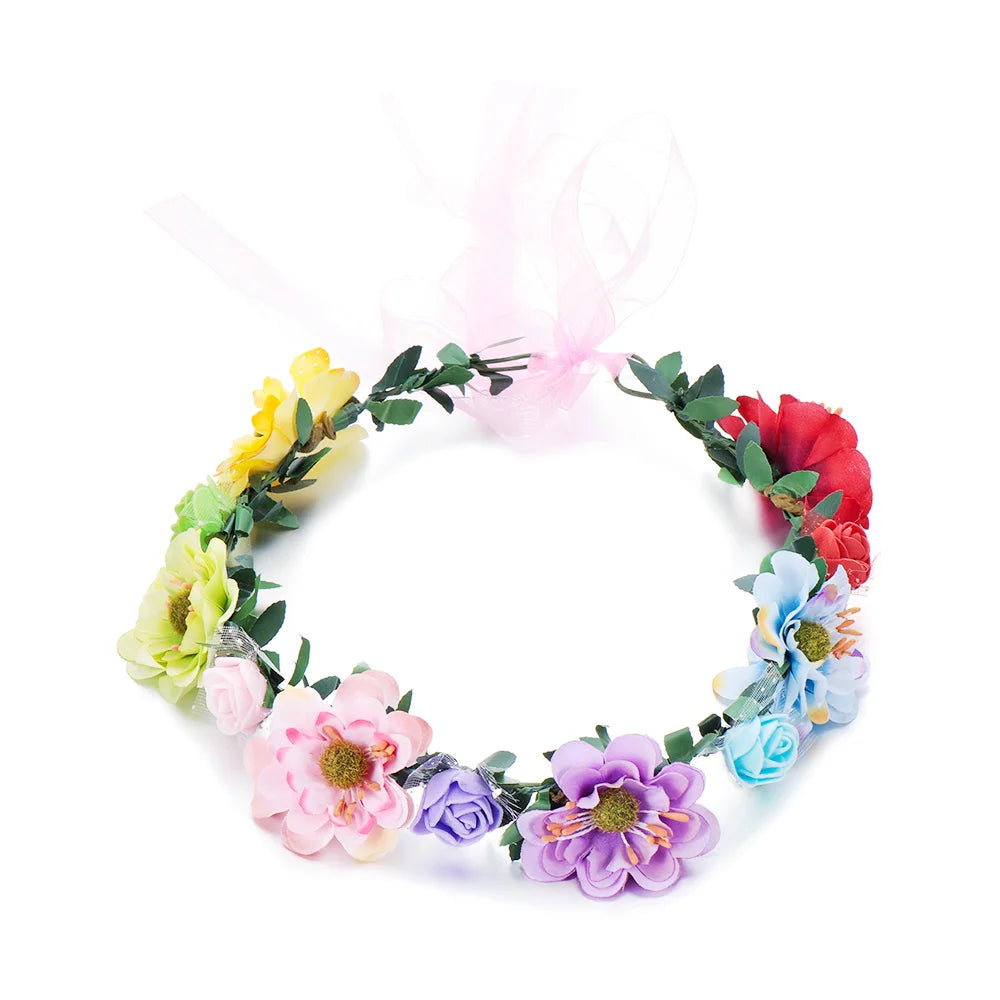A wreath of colorful flowers, including yellow, pink, red, and blue blooms, tied with a sheer pink ribbon.