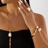 A close-up of a woman wearing a gold necklace and bracelet featuring imitation pearl jewelry.