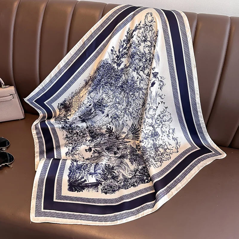 A silk scarf with a blue and white floral print draped over a brown leather sofa.