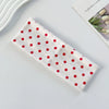 A white fabric headband with red polka dots is displayed on a light surface.