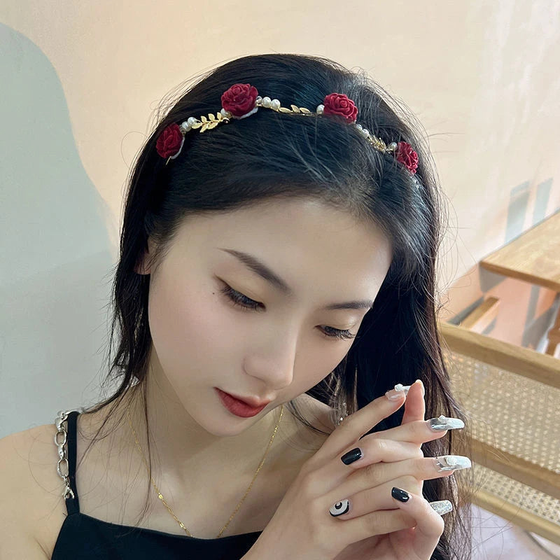 A close-up of a woman wearing an elegant rose vine headband hair accessory with dark hair.