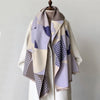 A beige and purple plaid cashmere scarf draped over a light colored coat.