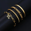 A stack of gold-toned stainless steel jewelry featuring a chain bracelet and a cross pendant.