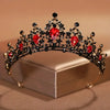 Diadema de cristal barroca negra y roja con intrincado diseño floral, exhibida en una caja de luz.