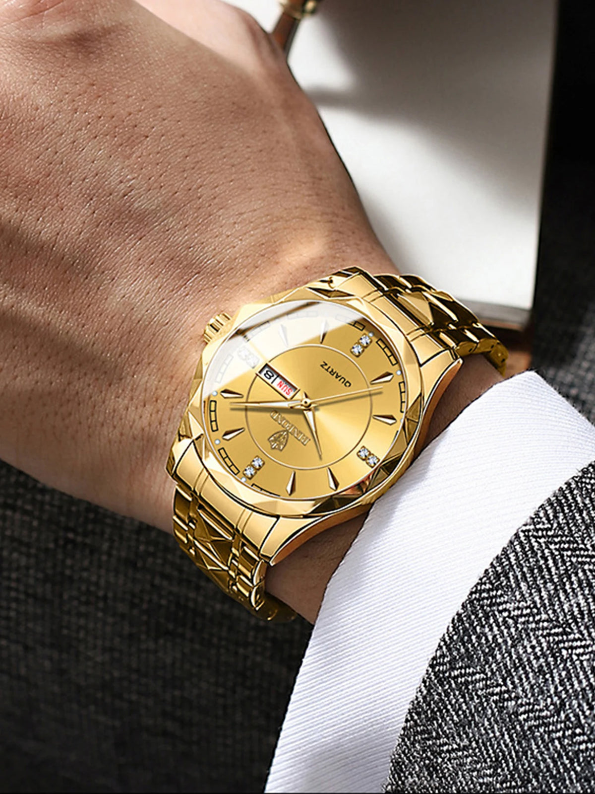 A close-up of a gold-toned stainless steel quartz watch worn on a wrist, paired with a white shirt and a textured jacket.