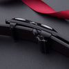 A close-up of a black leather belt with a buckle and a red ribbon, shown against a dark background.
