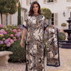 Eine Frau modelliert ein beige-braunes Leopardenmuster-Satin-Abaya-Schalset im Garten.