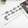 Cadena de cintura ovalada de plata delicada con eslabones decorativos, mostrada sobre un fondo blanco junto a un libro.