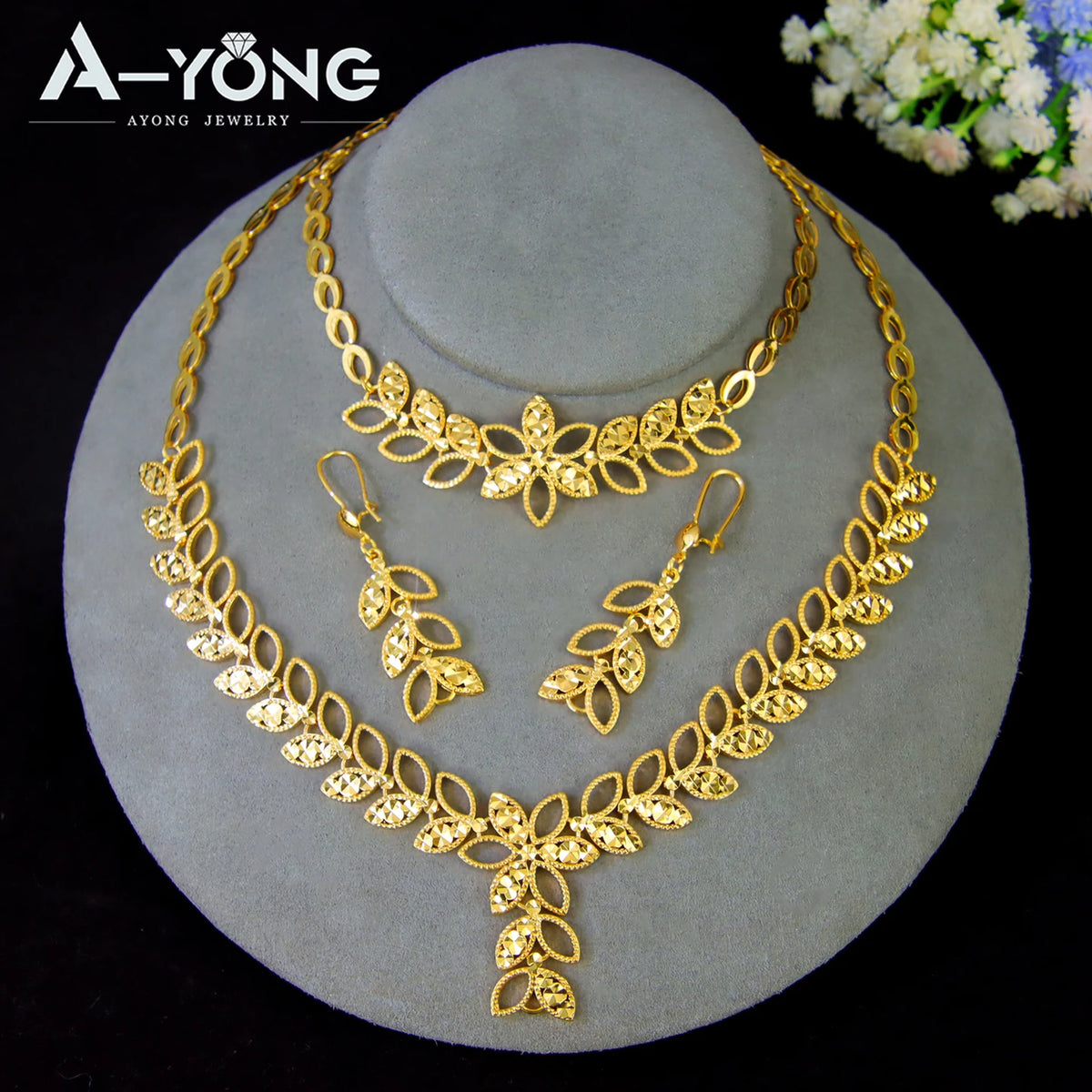 A set of luxury gold plated bridal jewelry featuring layered necklaces and floral pendants displayed on a stand.