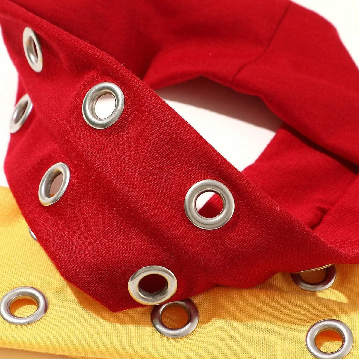 Red punk style metal hollow headband with silver grommets shown in a close-up view.