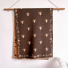 A dark brown pashmina shawl featuring a delicate floral print of small bees.