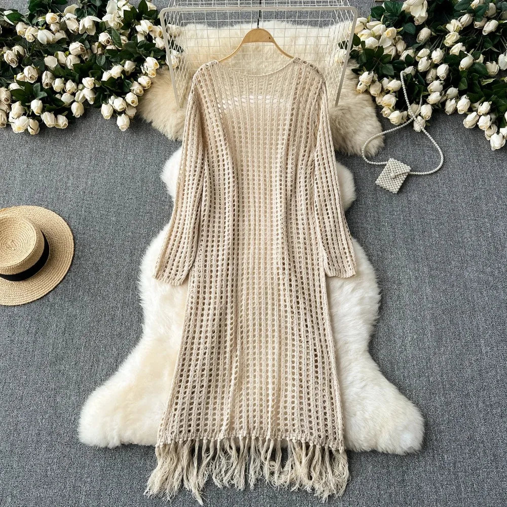A beige knitted shawl cardigan draped over a white fluffy fur garment, surrounded by white flowers.