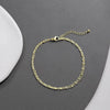 A delicate layered gold and silver plated anklet is displayed on a gray surface.
