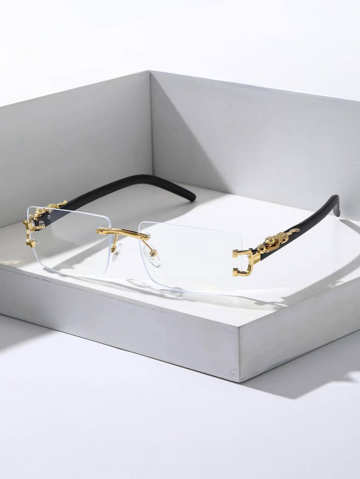 Trendy frameless rectangular sunglasses with gold accents resting in a white box.