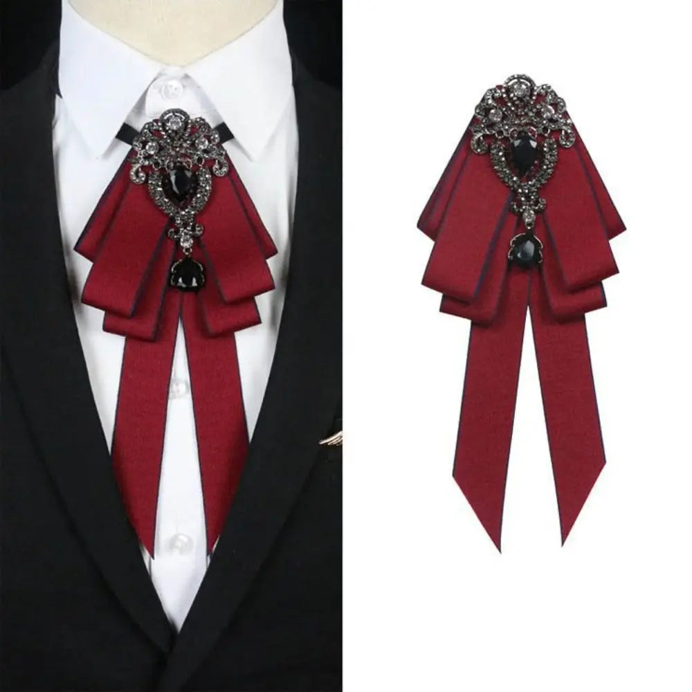 A deep red velvet bow tie with intricate silver rhinestone detailing worn on a white shirt.