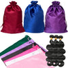 Three satin drawstring storage bags in red, blue, and purple next to a pink hair extension bundle.