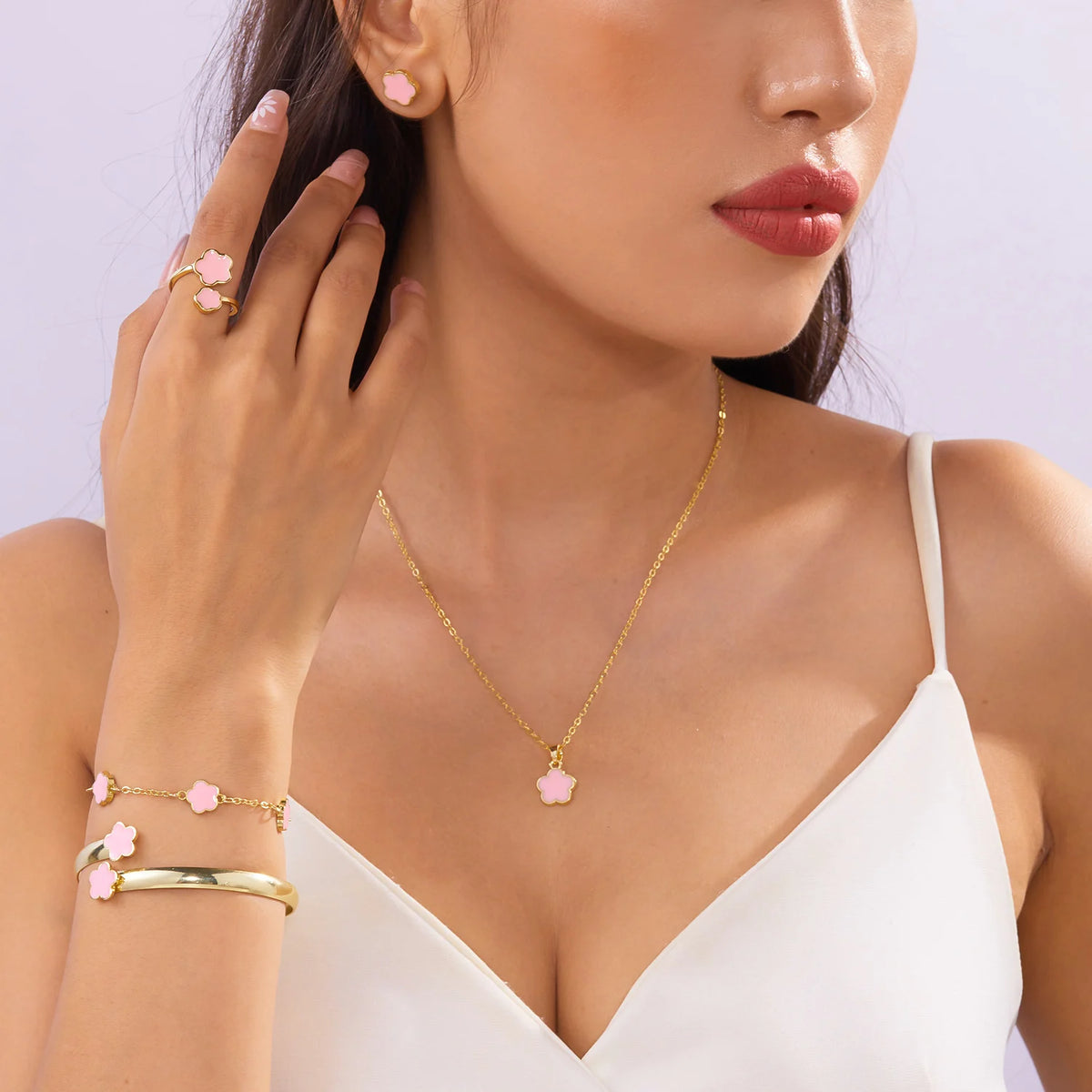 A close-up shot of a woman wearing a gold necklace and five enamel plum blossom bracelets on her wrist.