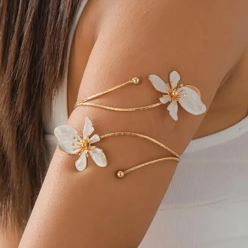 Gold floral open cuff armlet jewelry worn on a person's wrist.