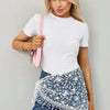 A woman models a white t-shirt and denim jeans with a floral lace scarf draped over her shoulder.