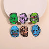 Sammlung von Emailpins mit Gesichtern verschiedener grüner, violetter und blauer Science-Fiction-Horrormonster.