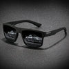 A pair of black polarized sunglasses resting on a dark, speckled surface with a blurred car reflection.
