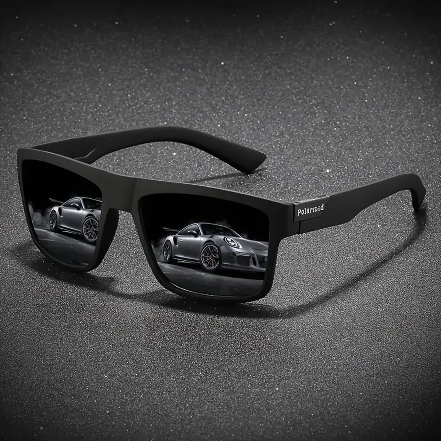 A pair of black polarized sunglasses resting on a dark, speckled surface with a blurred car reflection.