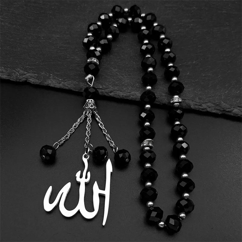 A black beaded necklace with a stainless steel Arabic calligraphy pendant on a dark background.